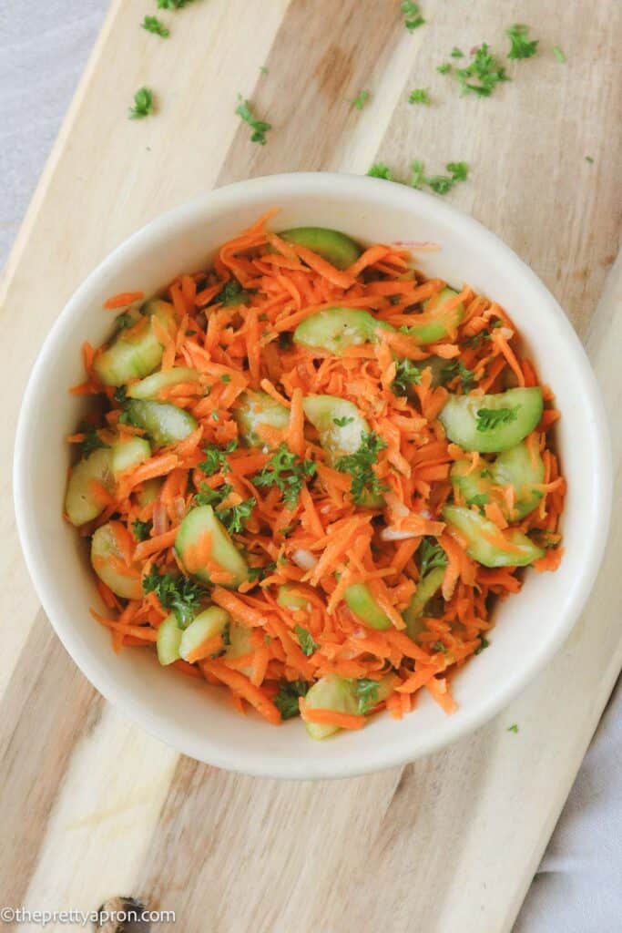 Carrots cucumber salad in bowl on wooden board
