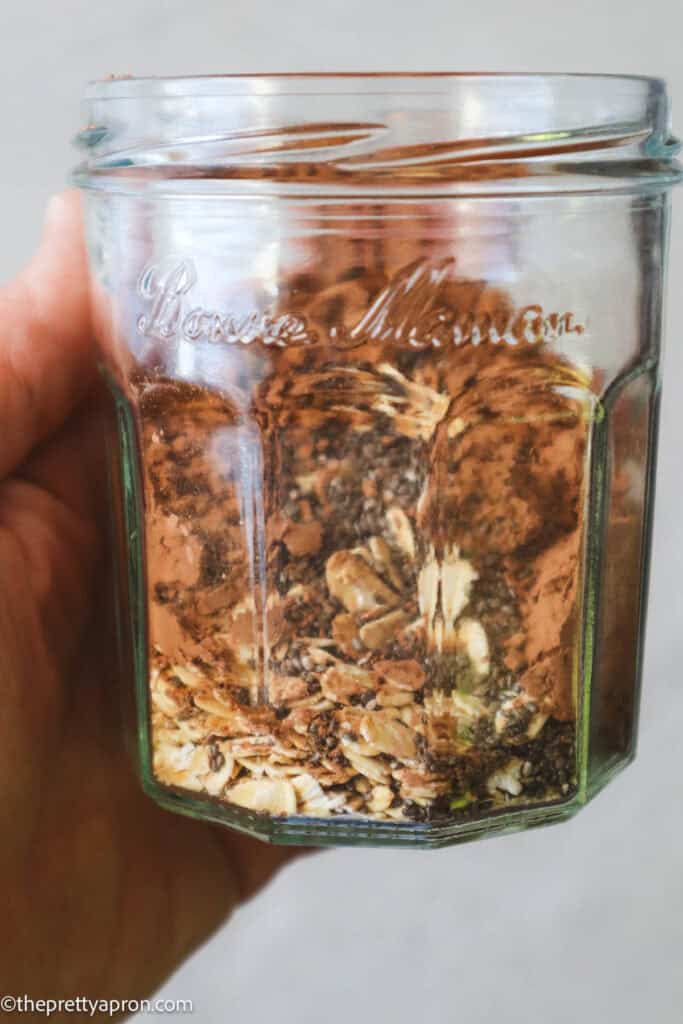 Hand holding Jam jar with oats, cacao, chia seeds