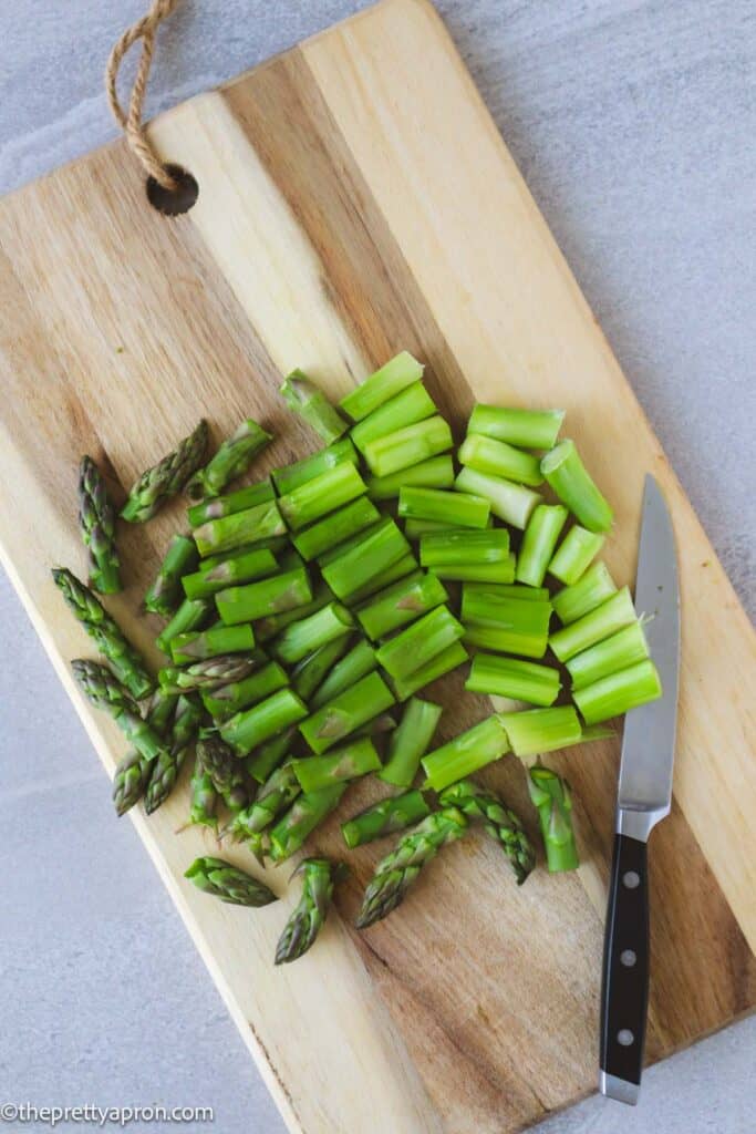 chopped asparagus on cutting board with knife