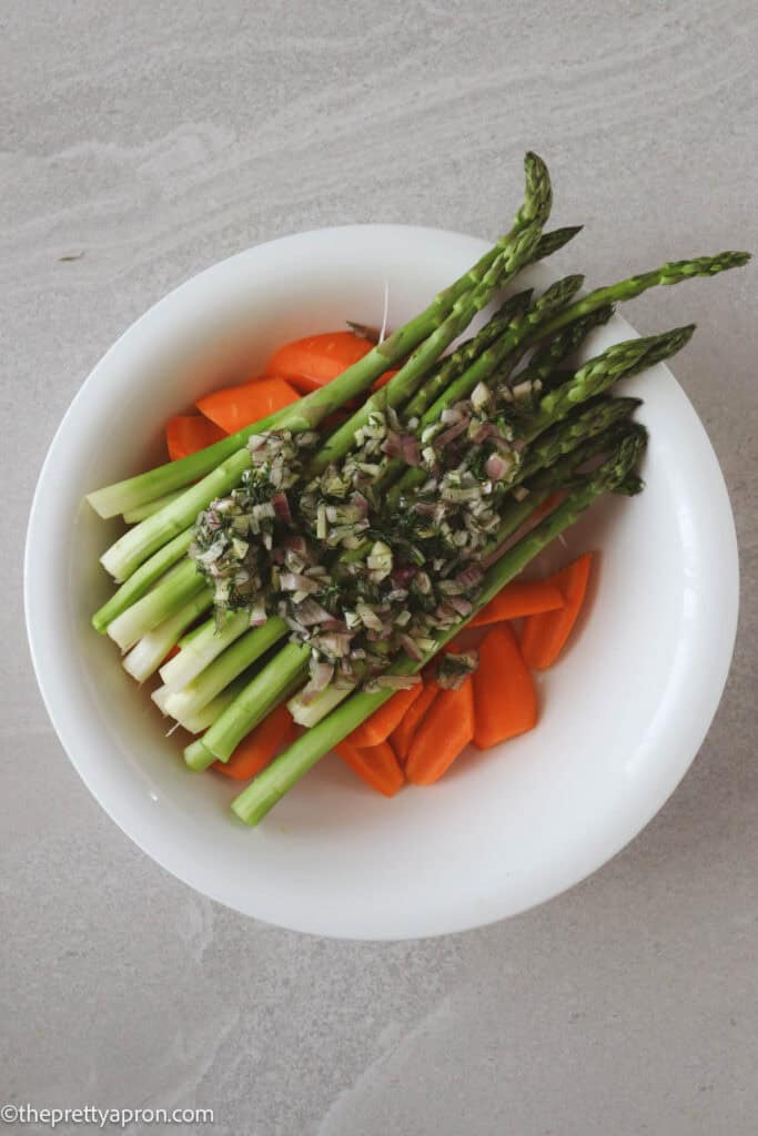 chopped carrots, asparagus in bowl with chopped shallots, garlic, dill, olive oil marinade poured on top