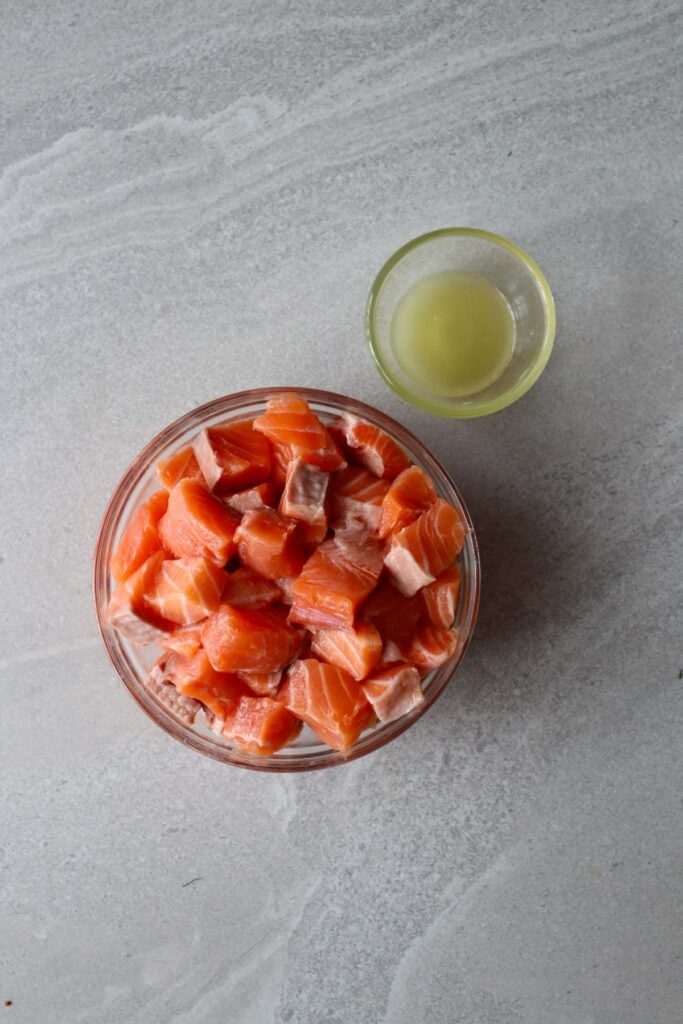salmon chopped in cubes and small bowl of lemon juice