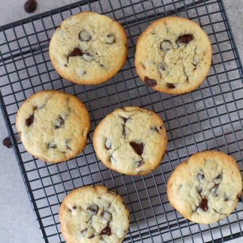 six chocolate chip cookies made with white sugar cooling on wire rack