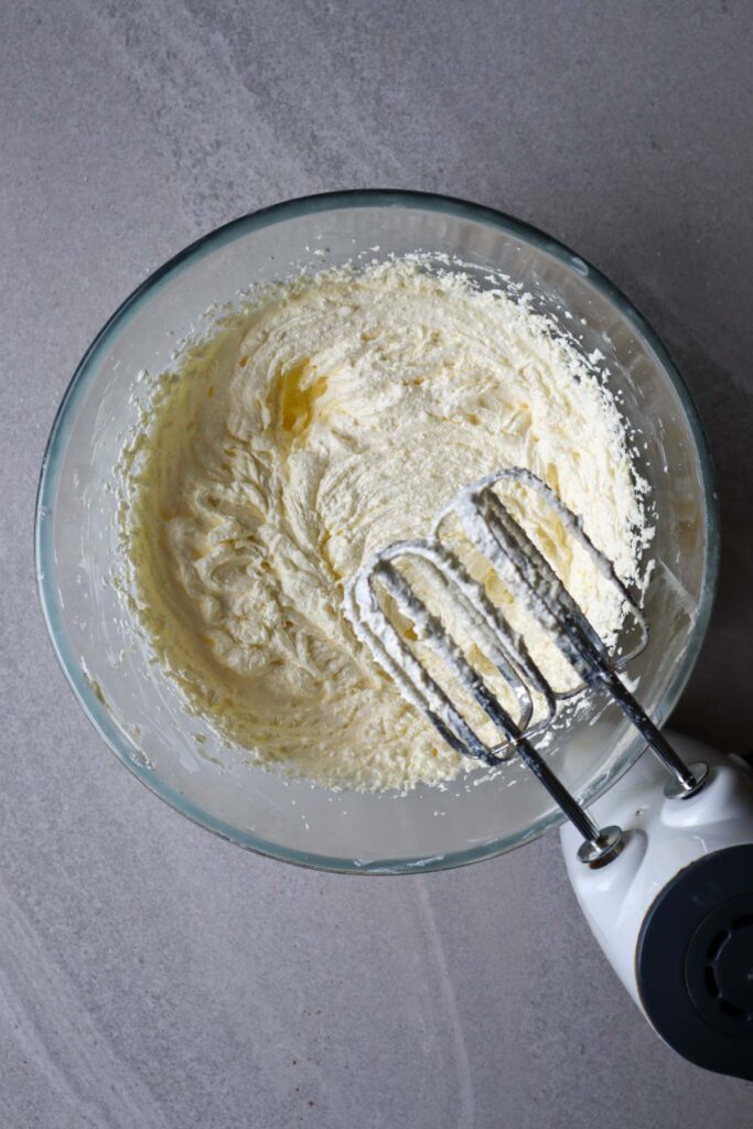 Creaming sugar and eggs in glass bowl with electric mixer
