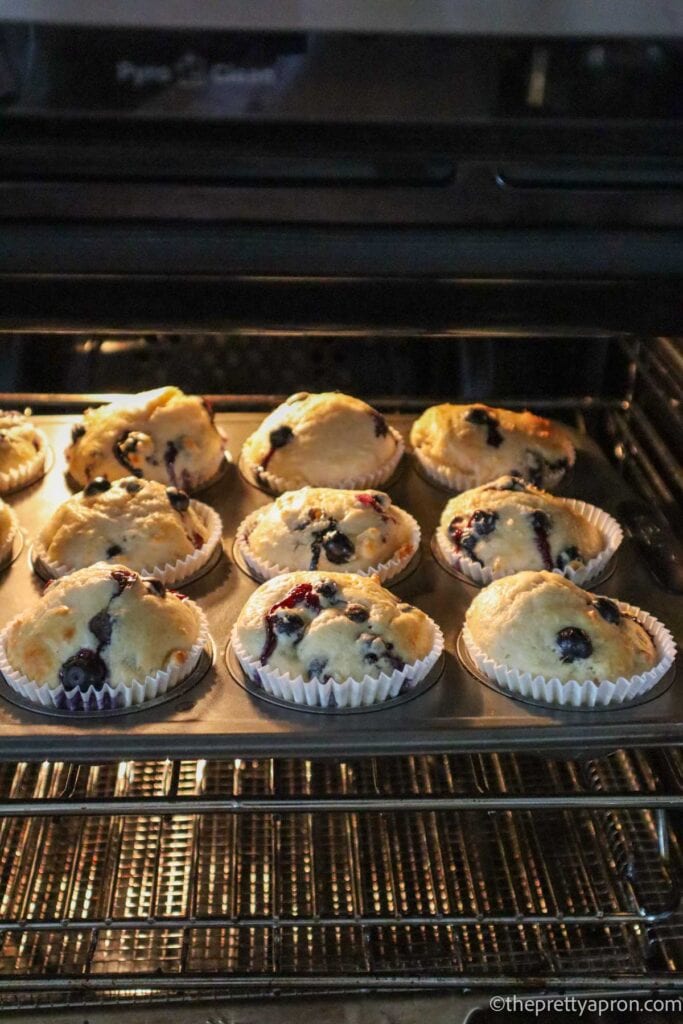 9 blueberry cottage cheese muffins baking in an oven