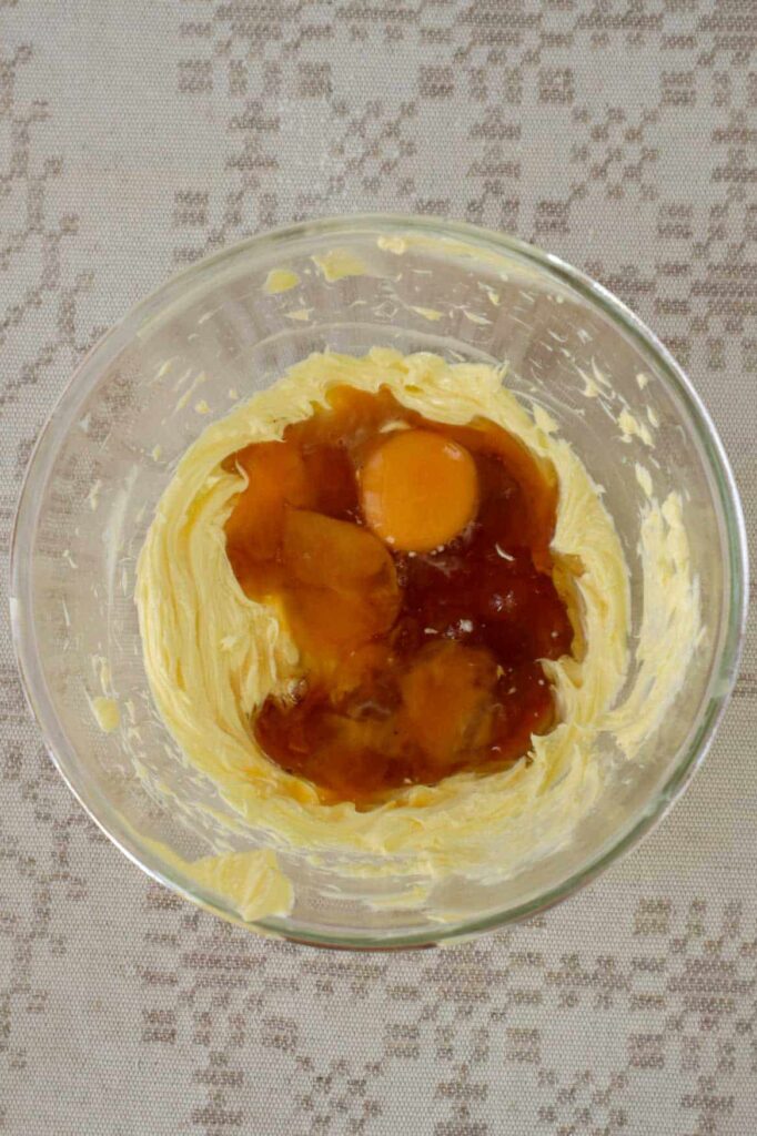 Whipped butter in glass bowl and two egg yolks and maple syrup added.