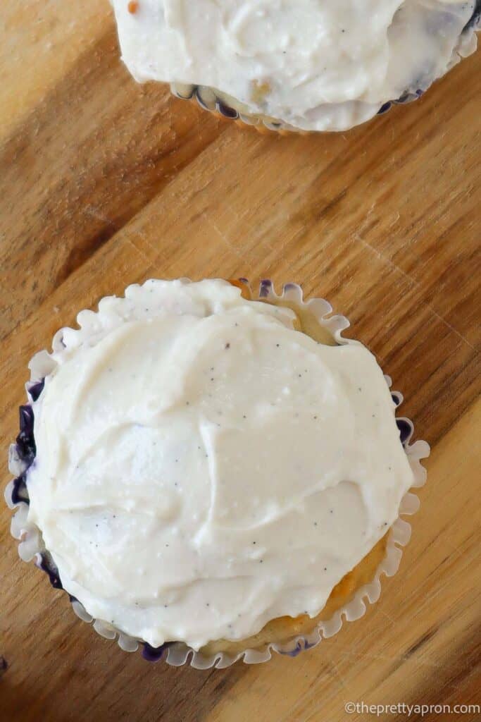 White cottage cheese frosting on muffin on a wooden board. Top view.