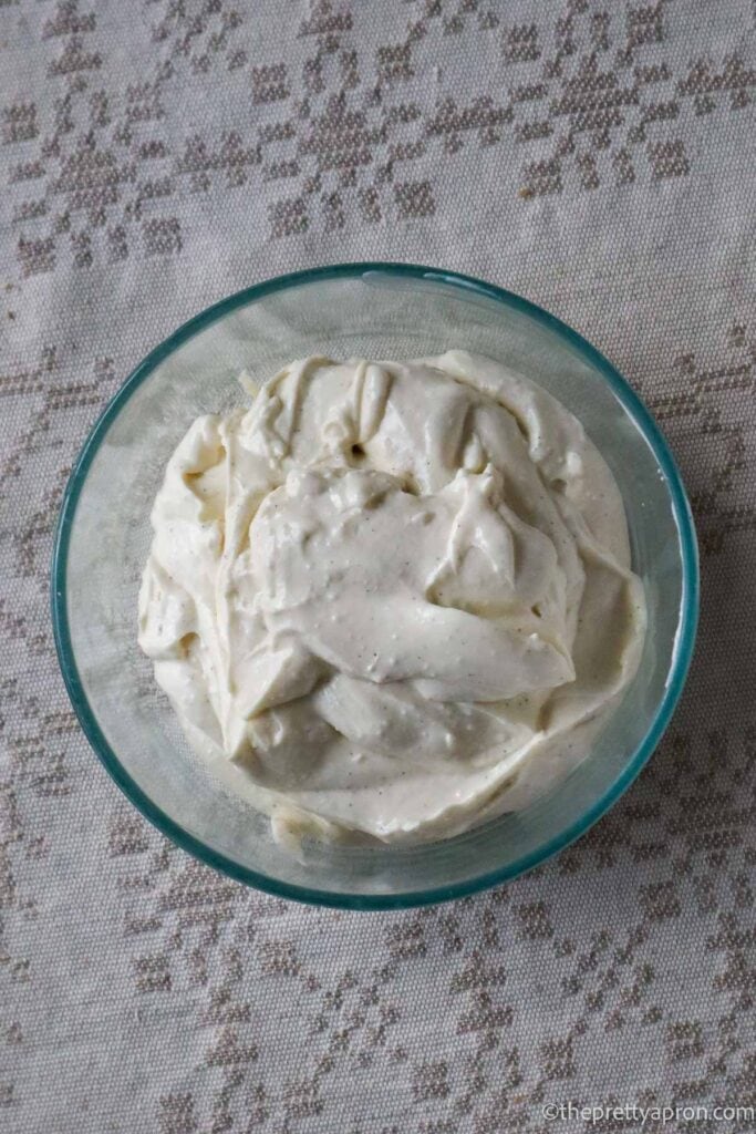 Cottage cheese frosting in a glass bowl on a linen tablecloth.