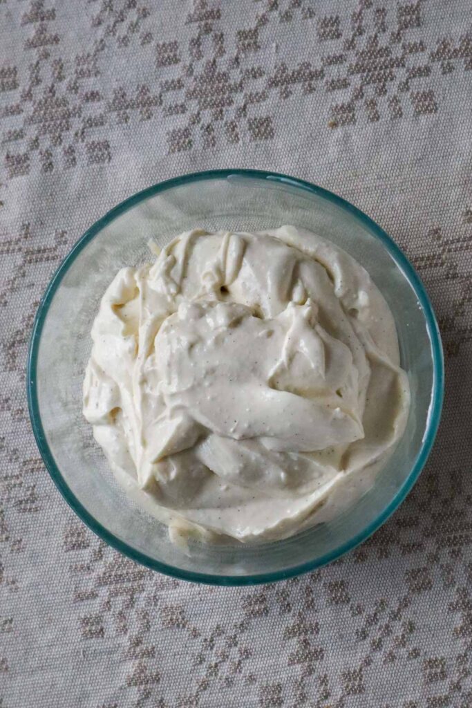 Cottage cheese frosting in a glass bowl on a linen tablecloth.