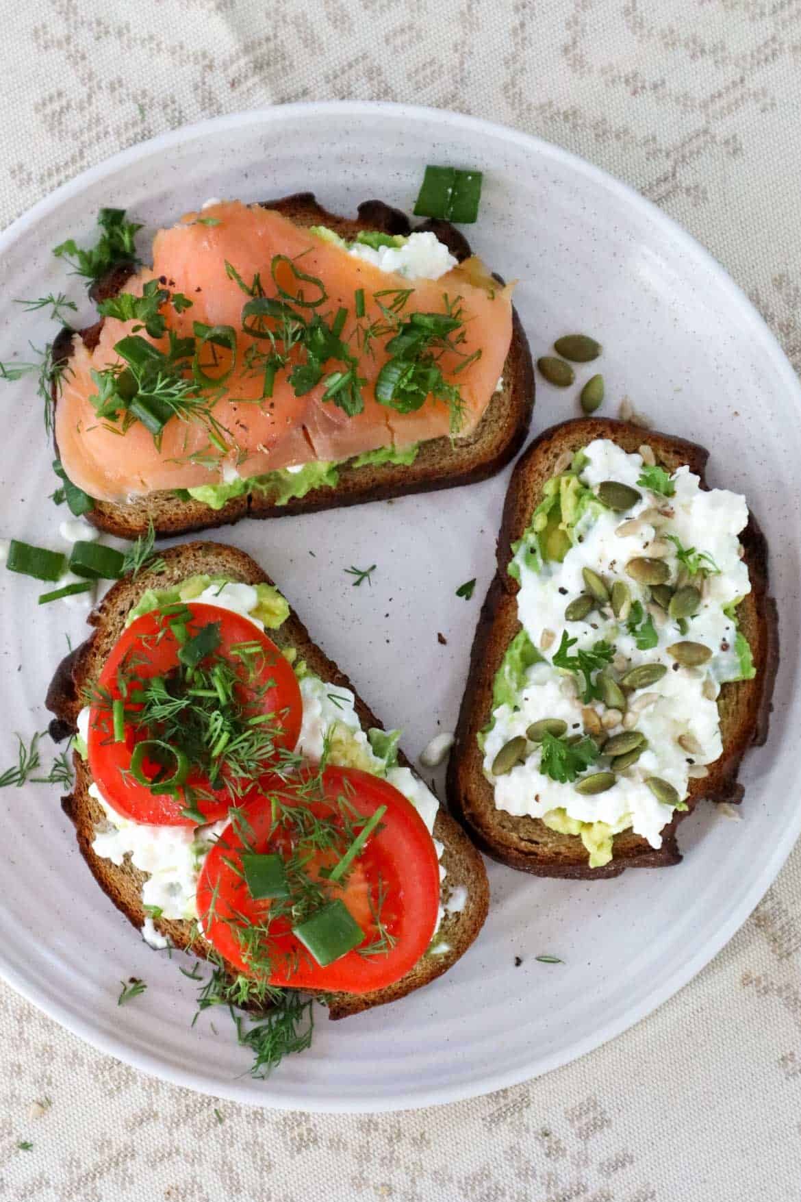 Trio of cottage cheese avocado toast with tomato, smoked salmon and seeds