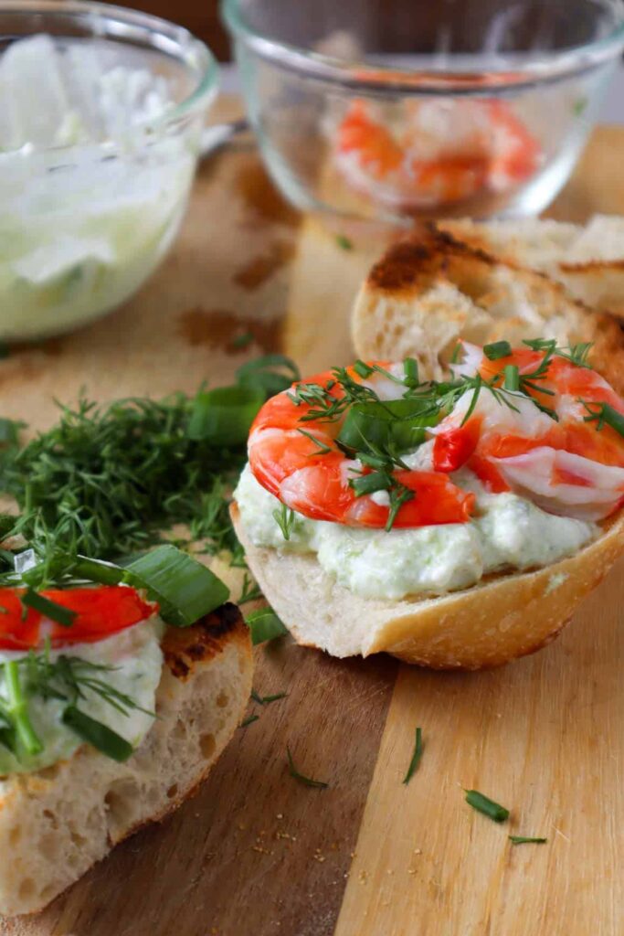 shrimp avocado toast on wooden board with herbs