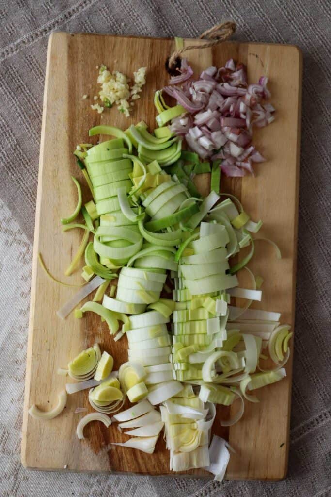 sliced leeks and shallot on a wooden cutting board