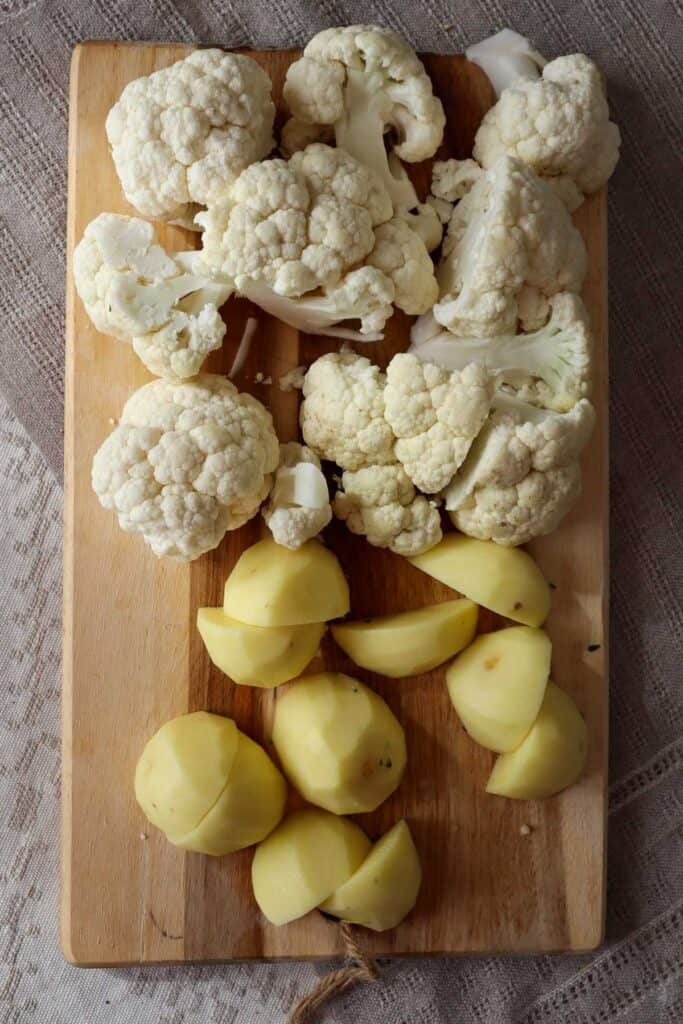 chopped cauliflower and potatoes on a wooden board