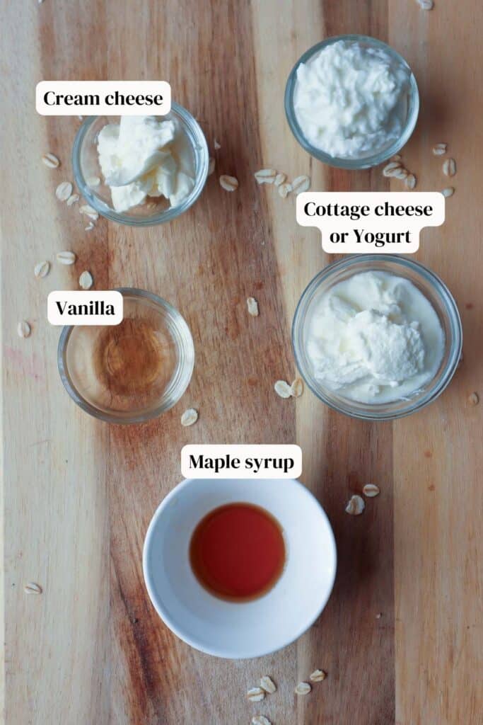 Cottage cheese, yogurt, cream cheese, vanilla and maple syrup in small glass bowls on a wooden board.