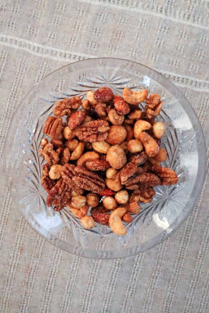 Nuts in a crystal bowl on a linen tablecloth laid out for a Christmas party.