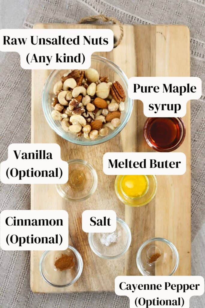 Raw unsalted mixed nuts on a wooden board with baking ingredients including maple syrup, butter, vanilla and salt.
