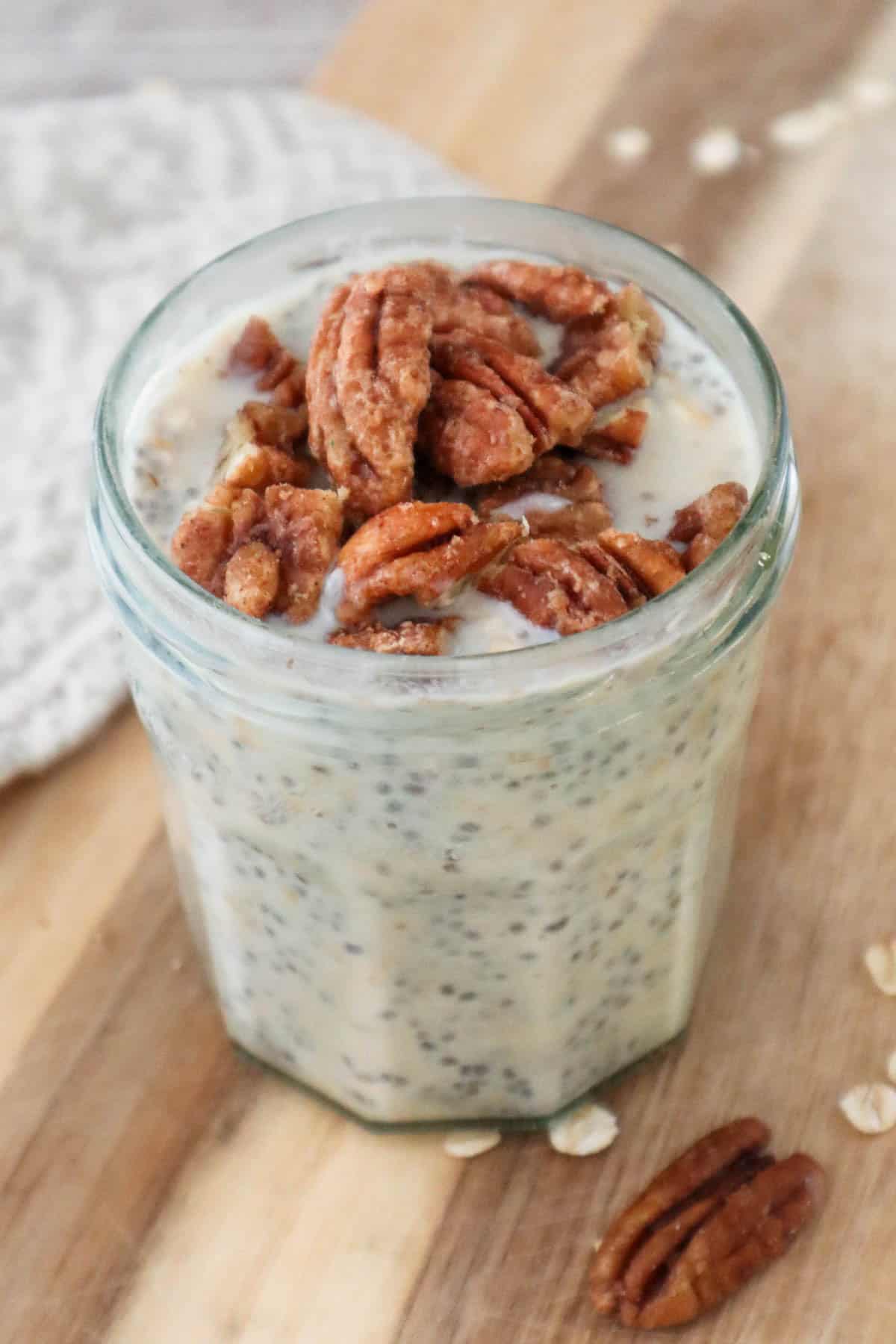 Maple overnight oats with chia seeds and yogurt and maple pecans on wooden board.
