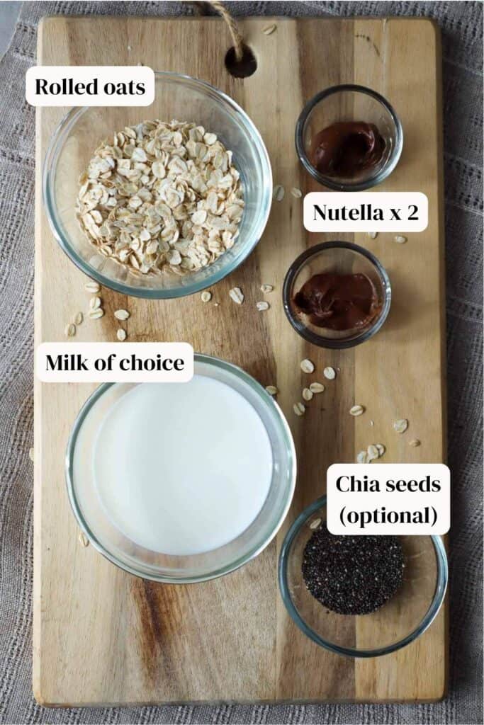 Oats, milk, chia seeds and nutella in glass bowls on wooden board.