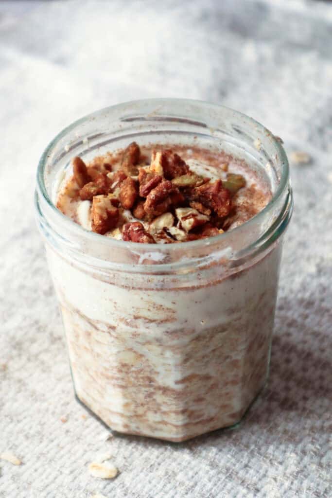 Cinnamon roll overnight oats in glass jam jar placed in linen tablecloth.