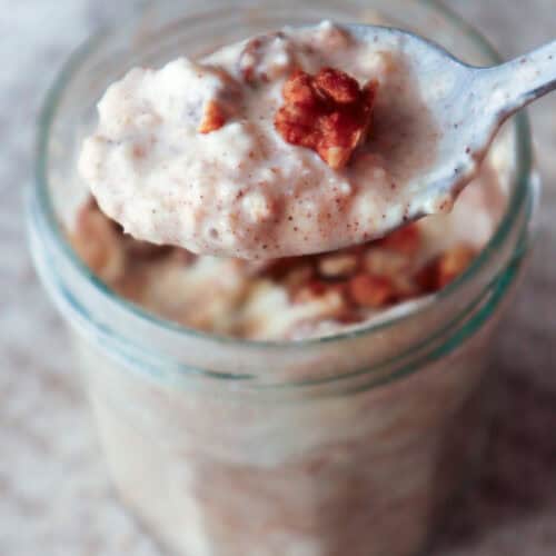 spoonful of creamy cinnamon roll overnight oats with pecan taken from glass jar.
