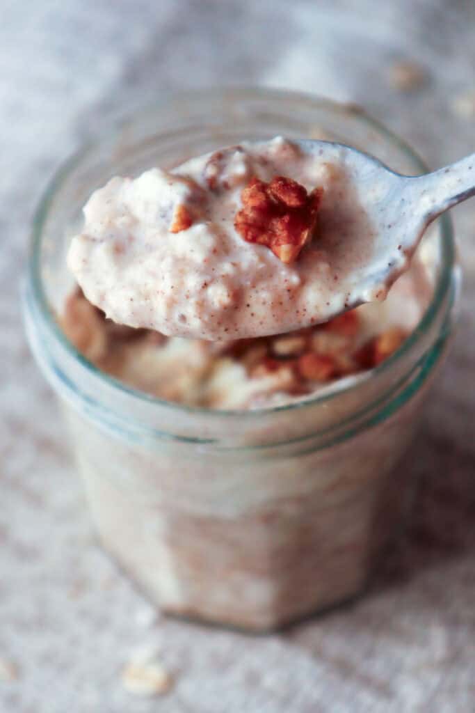 spoonful of creamy oats with pecan taken from glass jar.