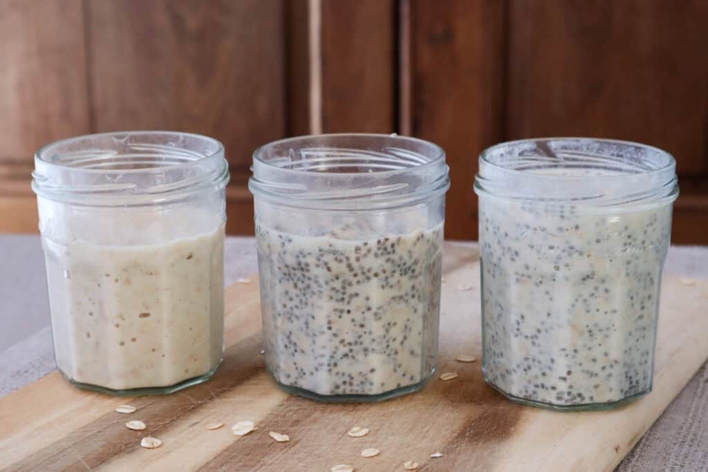 Three jars of breakfast mixture in glass jars on wooden board.