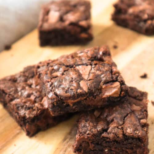 Five chocolate chocolate chip cookie bars on wooden board.