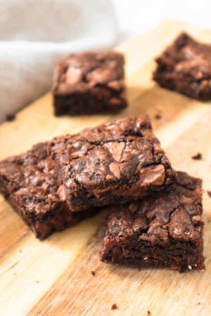 Five chocolate chocolate chip cookie bars on wooden board.