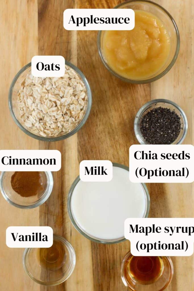 Applesauce, milk, chia seeds, maple syrup, cinnamon, vanilla in small glass bowls on wooden board.