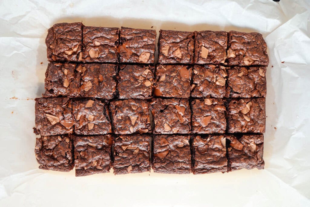 Twenty four cookie bars cut into squares in a dish lined with parchment paper.