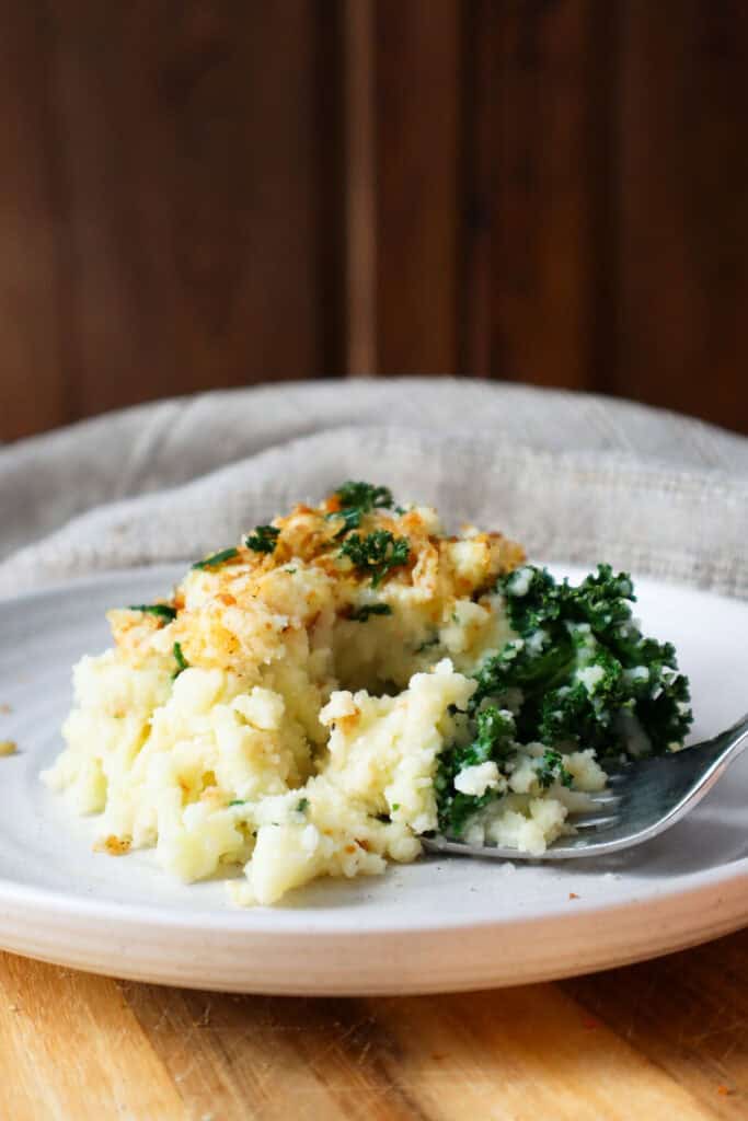Cottage cheese mashed potatoes with kale on a small beige dish.