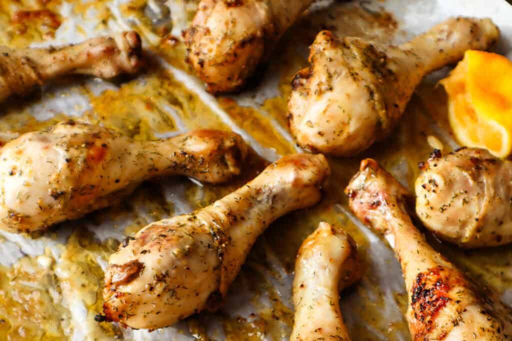 Six chicken drumsticks roasted on parchment paper.