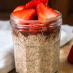 Nutella overnight oats topped with sliced strawberries on a wooden board.