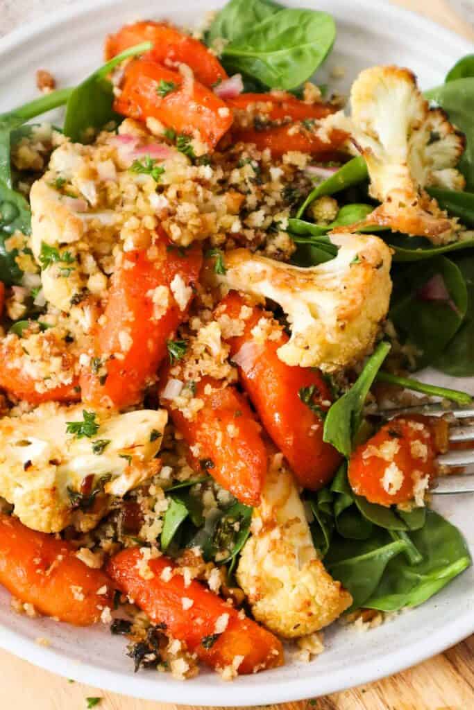 Roasted carrots and cauliflower with walnut panko crumbs on bed of baby spinach.