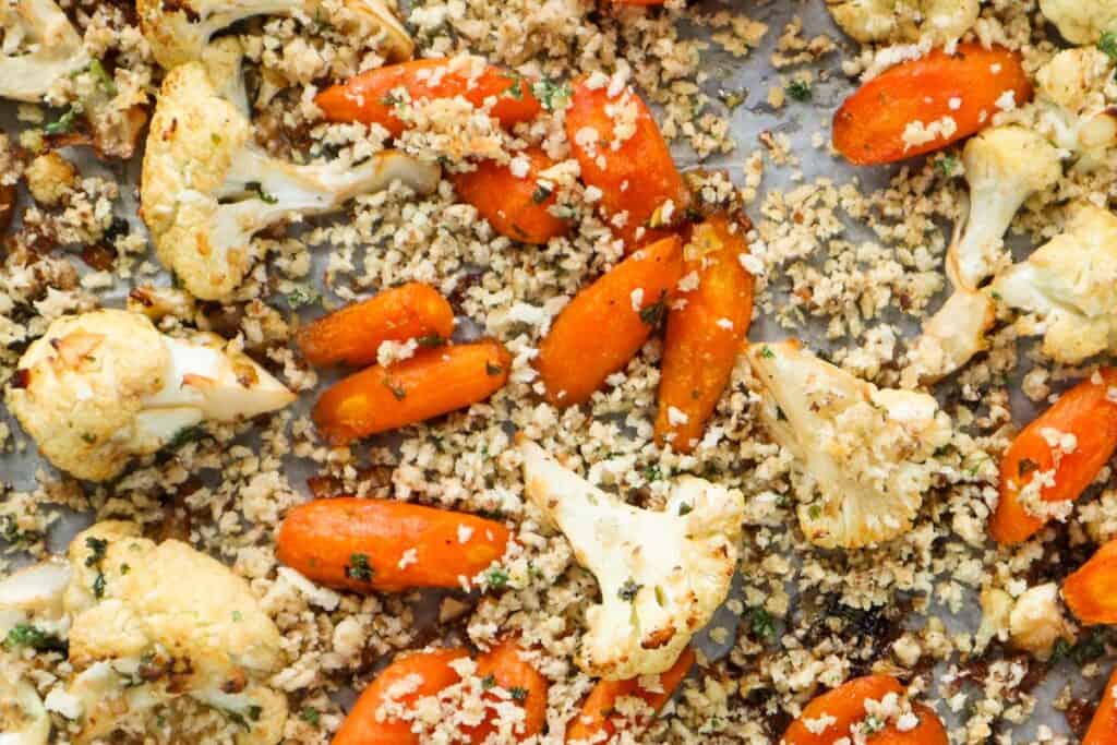 Close up of roasted carrots and cauliflower with panko crumbs on sheet pan.
