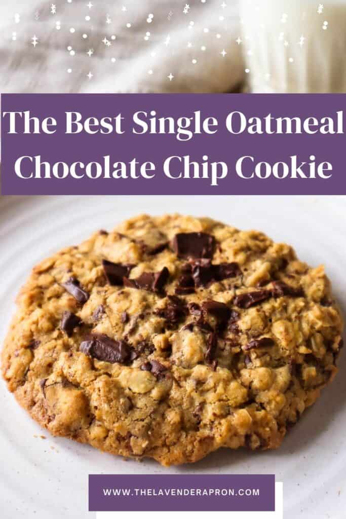 One oatmeal chocolate chip cookie on beige plate with glass of milk in background.