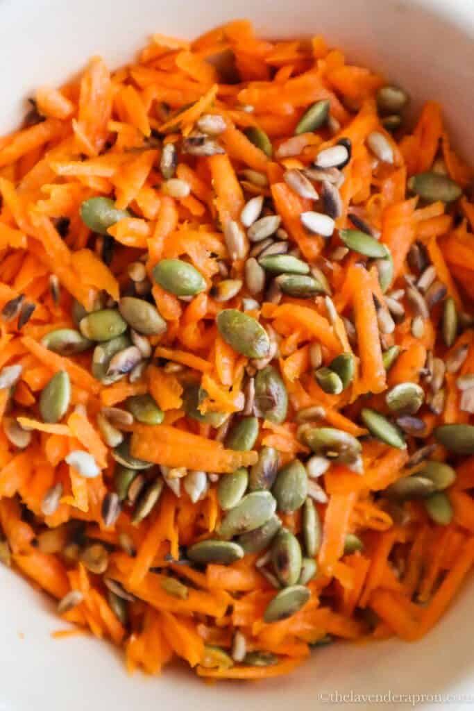 Close up of grated carrot with toasted pumpkin nd sesame seeds.