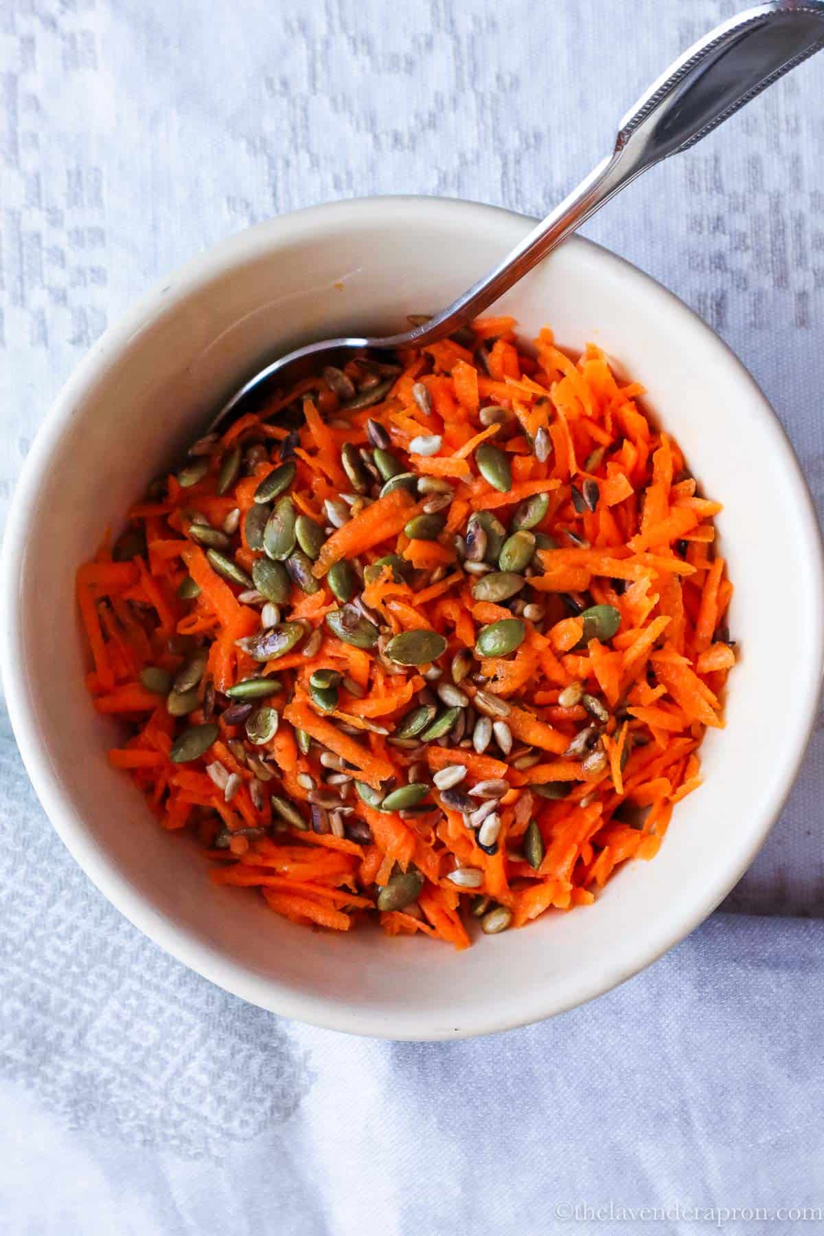 French carrot salad with roasted pumpkin and sesame seeds in bowl with a spoon.