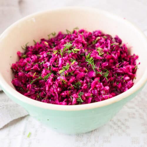 Red cabbage salad recipe with dill in a light green bowl.
