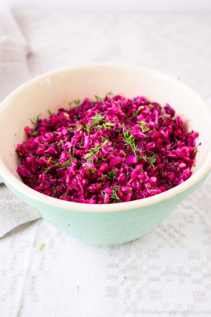 Red cabbage salad recipe with dill in a light green bowl.