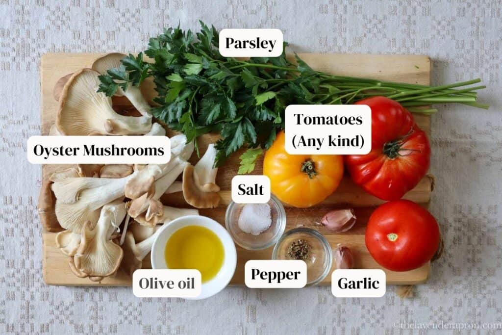 Ingredients for the best oyster mushroom recipe labelled. Ingredients include oyster mushrooms, tomatoes, parsley, olive oil and garlic.