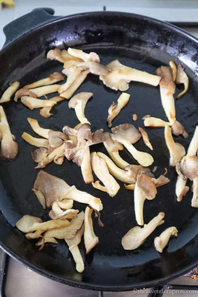 Sautéing mushrooms in a black cast iron skillet.