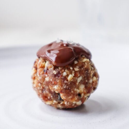 Chocolate almond ball with a pinch of sea salt on a white plate.