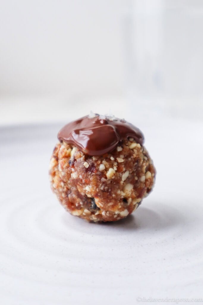 Chocolate almond ball with a pinch of sea salt on a white plate.
