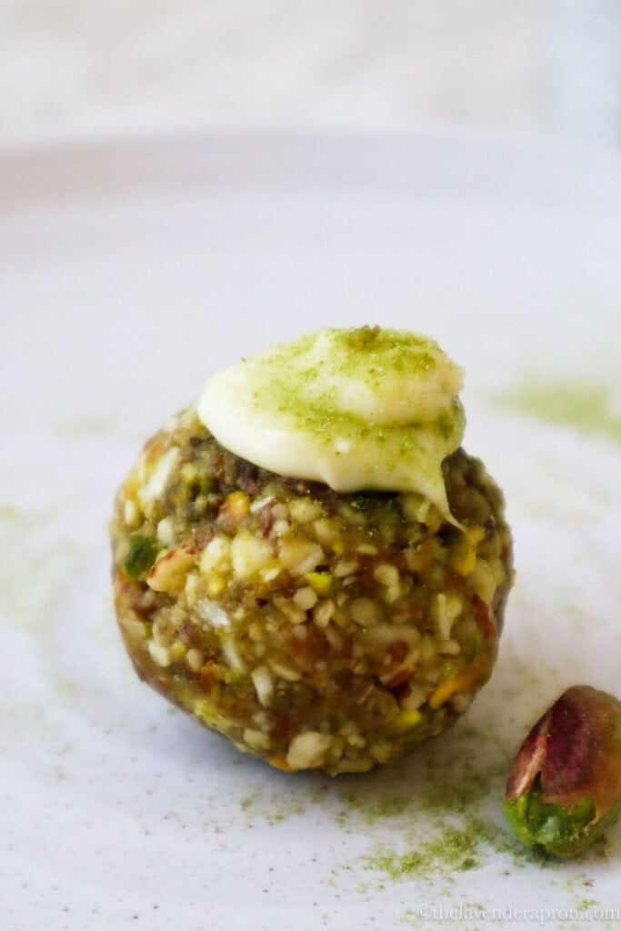 Matcha pistachio energy ball topped with white chocolate on a beige plate.