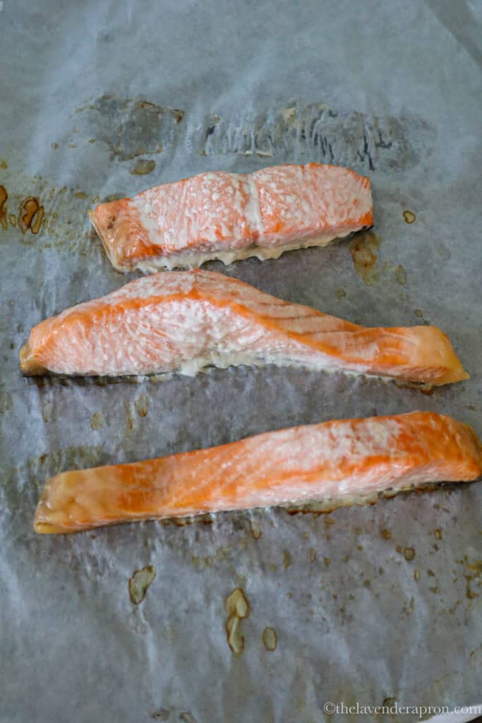 Three pieces of salmon baked on parchment paper.