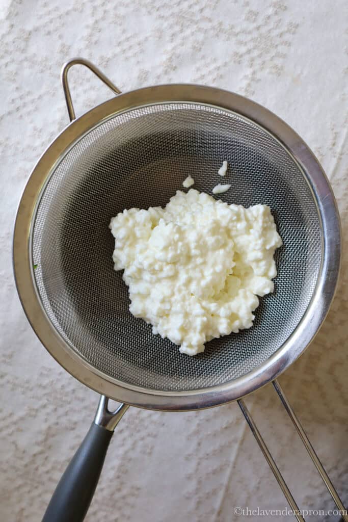 Rinsing and draining the cottage cheese over a strainer.