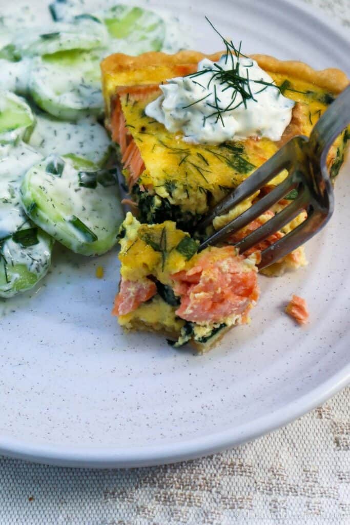 Taking a forkful of the spinach and salmon quiche topped with a dollop of sour cream and fresh dill.