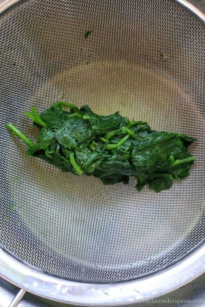 Squeezing the spinach until all the moisture is out.