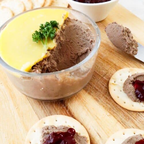 easy chicken liver pâté in a glass jar with butter seal, water crackers and lingonberry jam on a wooden board.