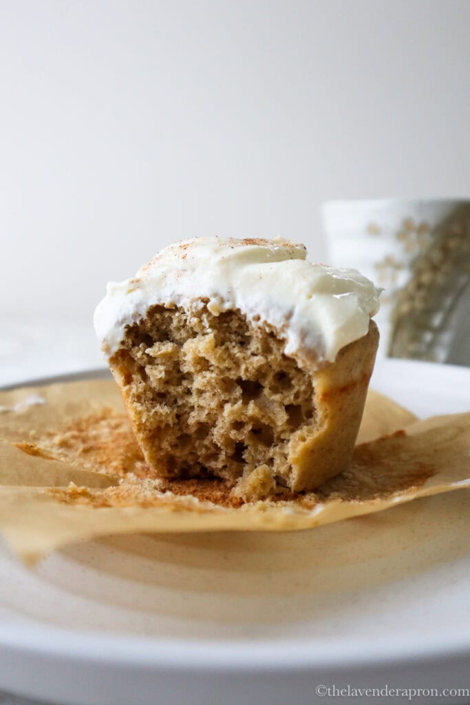 Taking a bite out of a muffin with cottage cheese frosting spread generously on top.